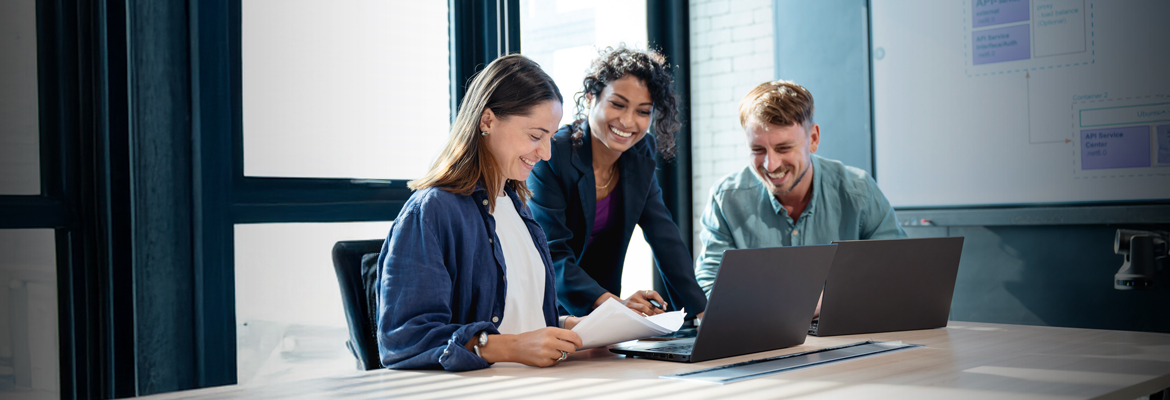 Three people working over laptops in a conference room